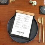 Klemmbrett_Holz_Esche_Mood_1 Leder-Menüboard mit Getränkekarte auf einem gedeckten Restauranttisch
